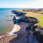 aerial-shot-clear-blue-sea-grassy-shore_11zon