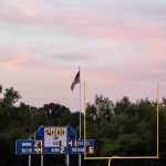 illuminated-scoreboard-by-flag-against-trees_11zon